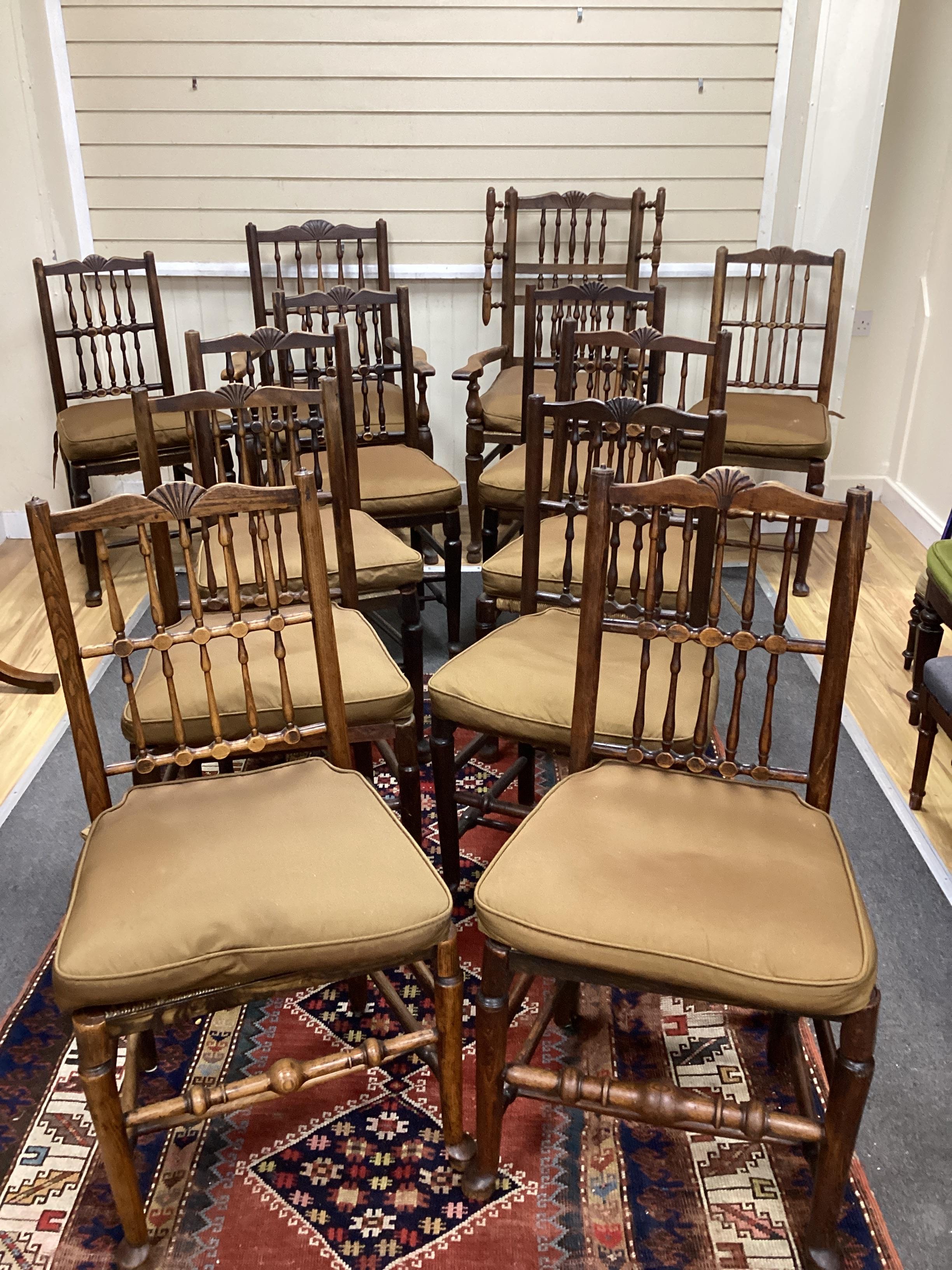 A harlequin set of twelve 19th century Lancashire ash elm and beech rush seat spindle back chairs with loose cushion squab seats, two with arms